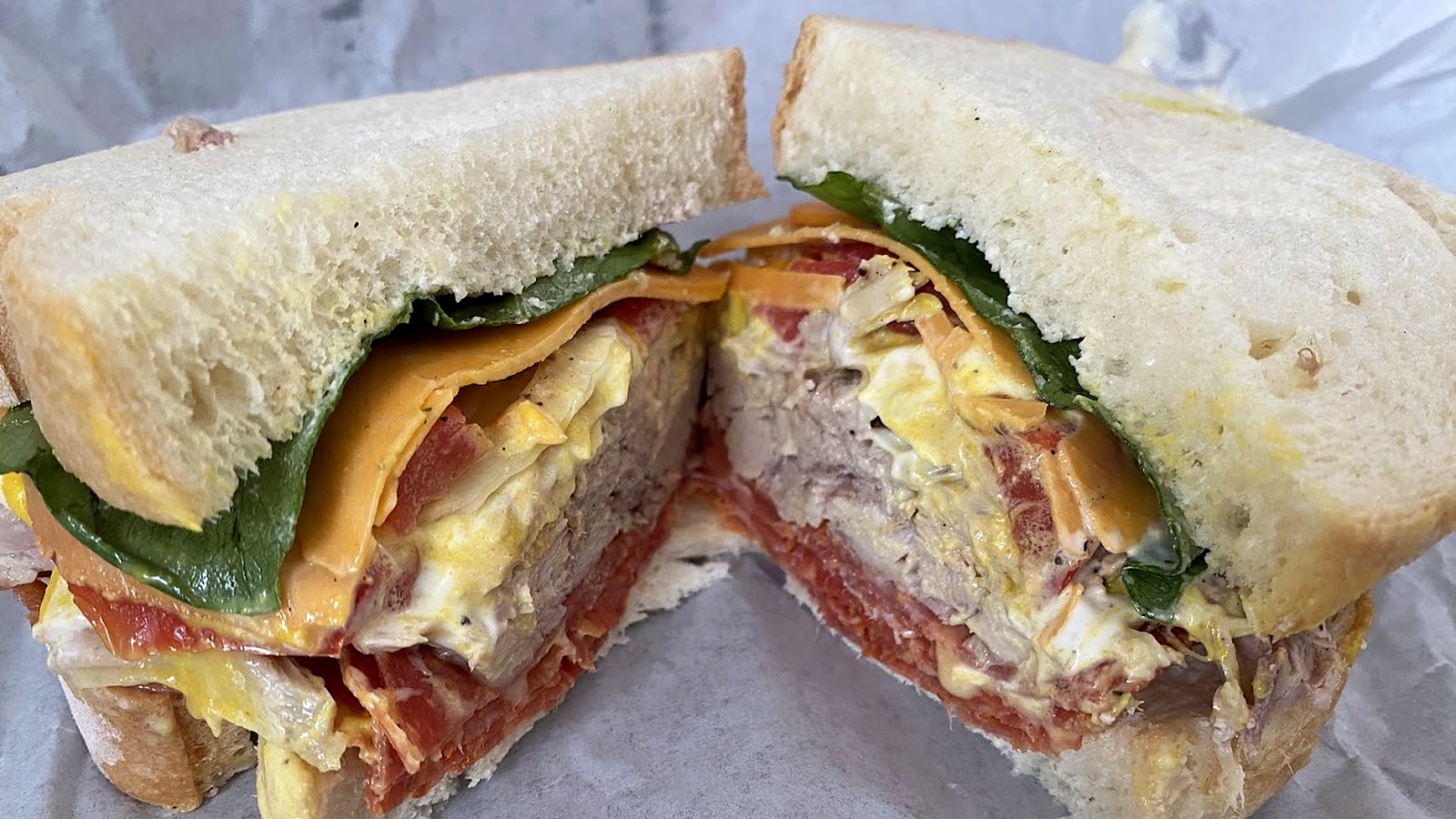 Stacked sandwich on fresh-baked bread with real roasted meat, cheddar, spinach and tomato