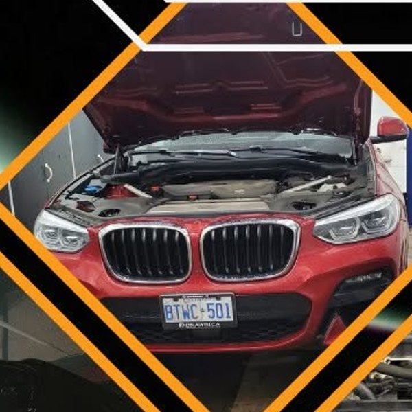 A red BMW with the hood up for diagnostics at JK Motors